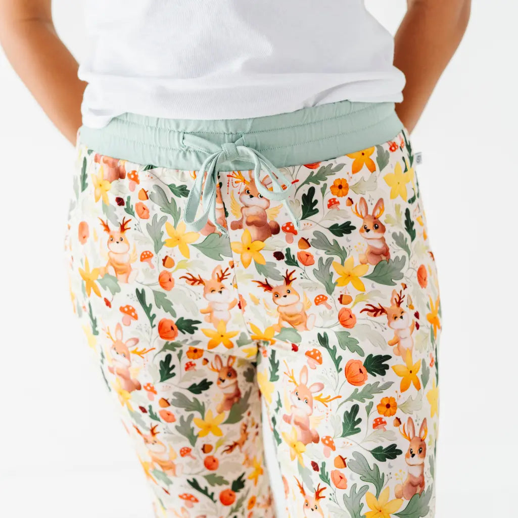 A close up of a sage drawstring waistband on woodland print pajama pants worn with a white tee.